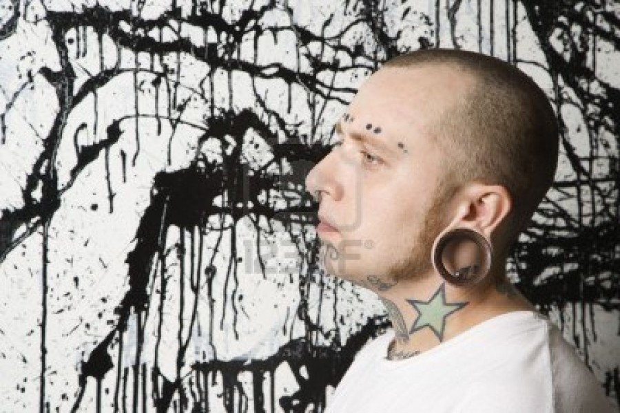 Tattooed And Pierced Man Against Paint Splattered Background